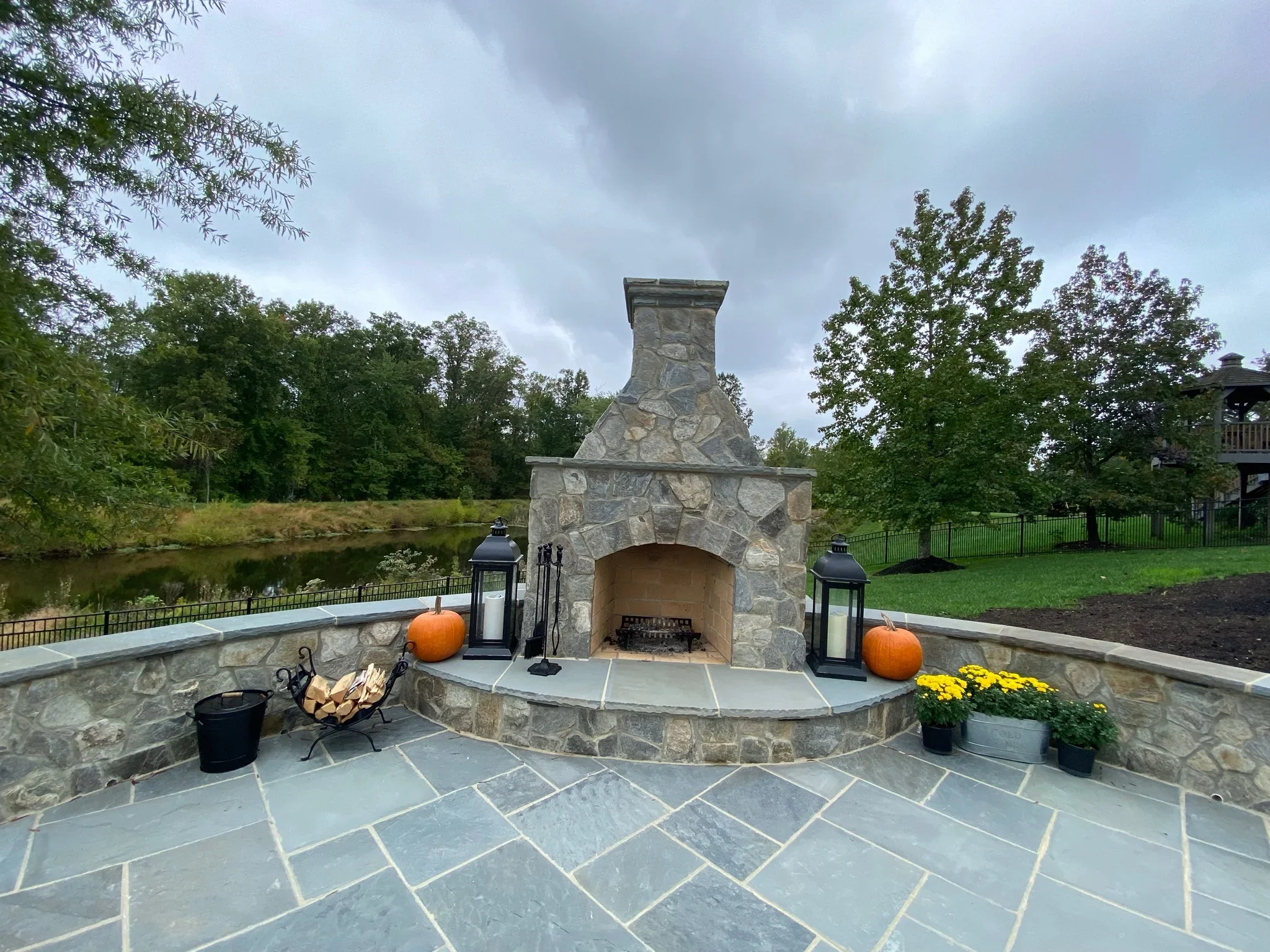 Stone fireplace with arched opening and curved slate patio with geometric pattern