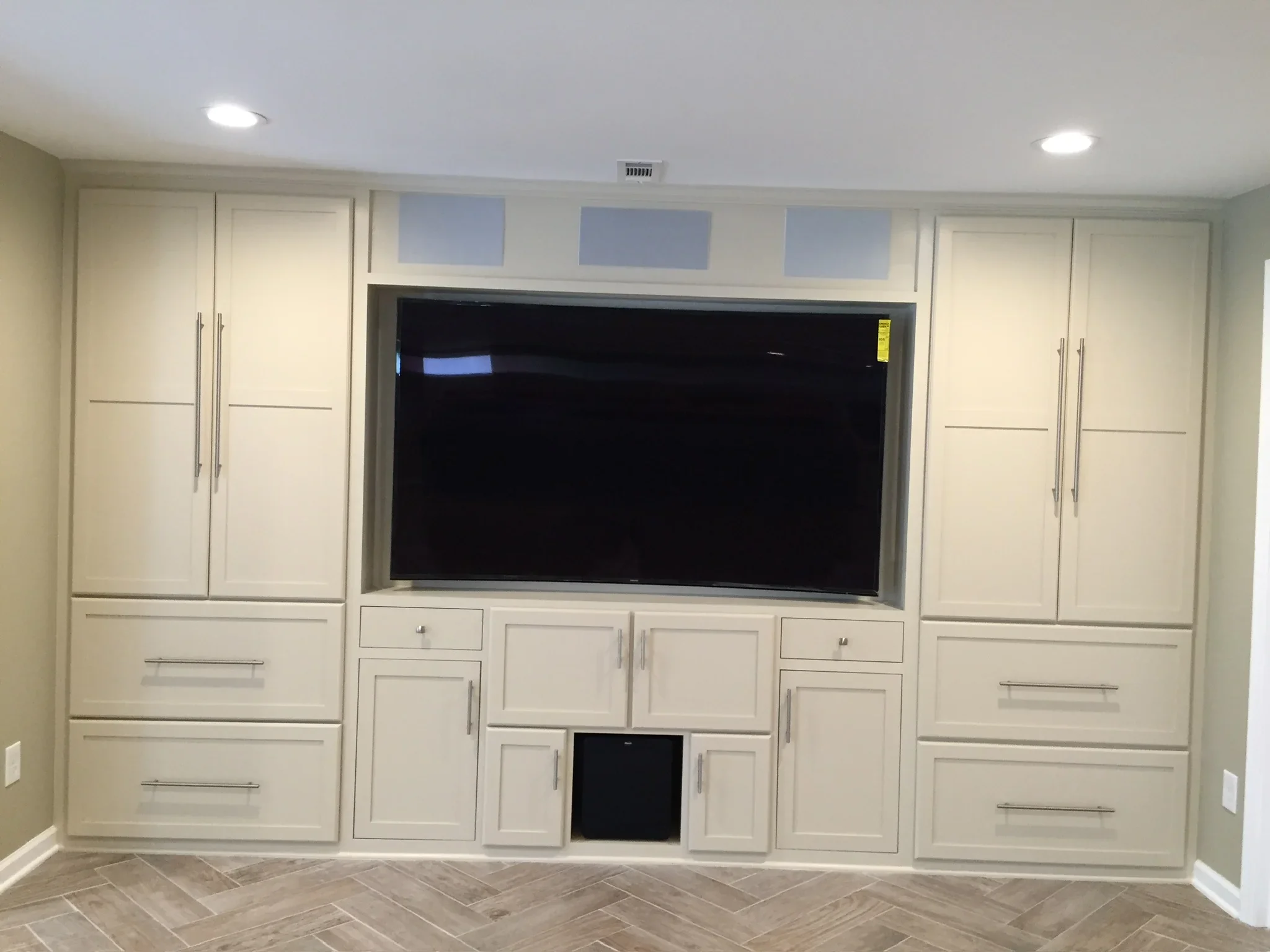 Cream cabinetry entertainment center with recessed TV, glass doors, drawers, and chrome hardware