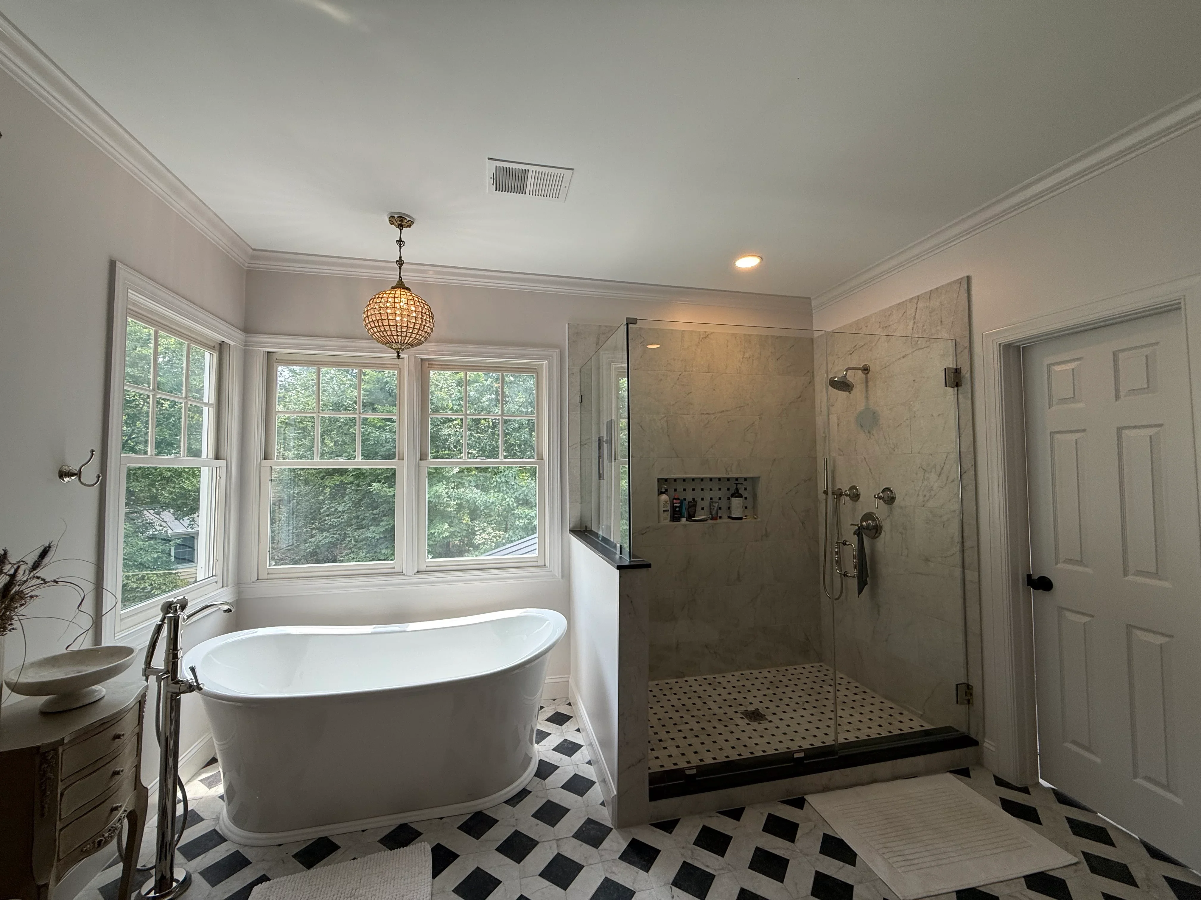 Master bath with freestanding tub, frameless glass shower, marble tile, geometric floor pattern