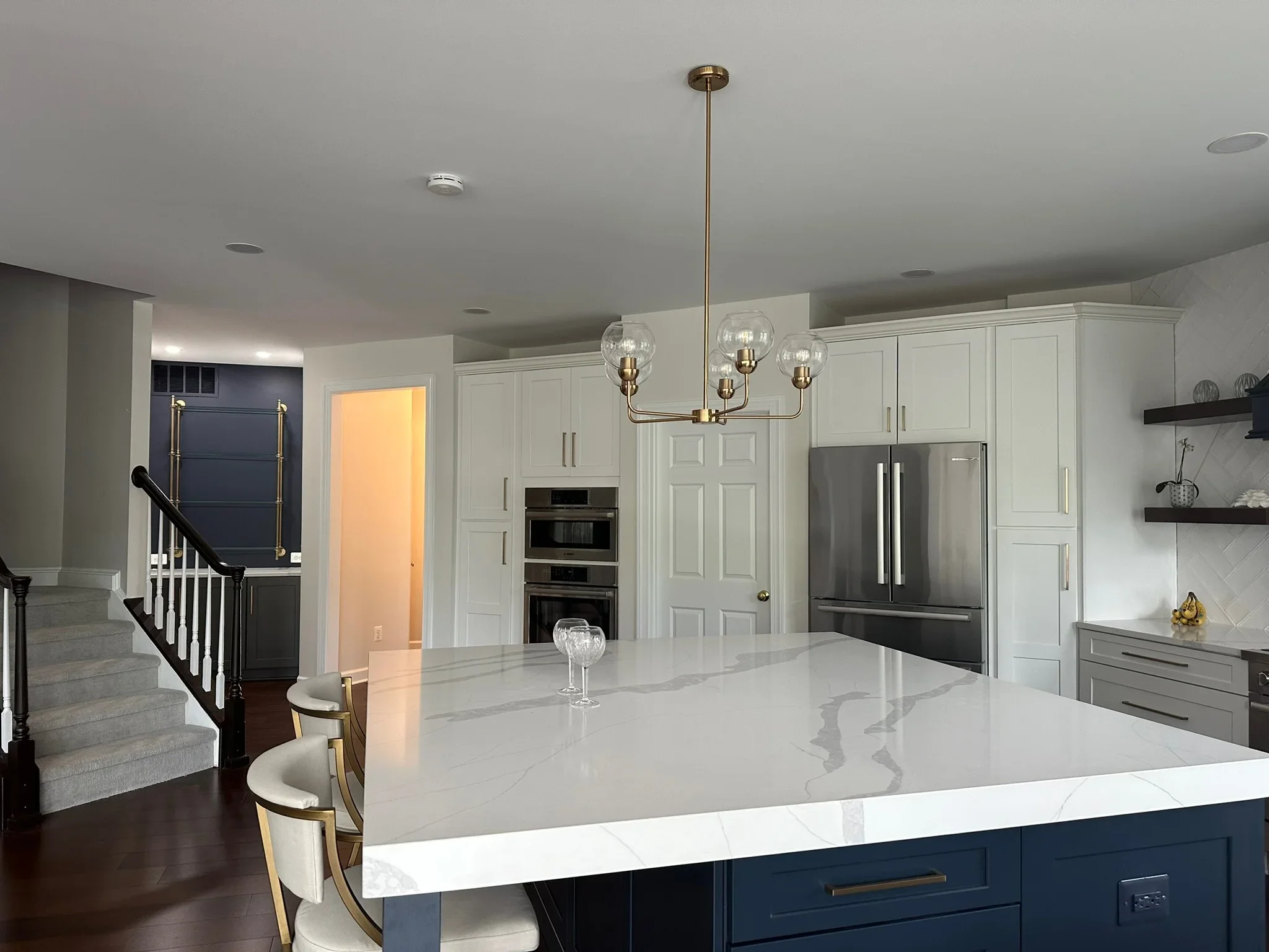 Modern kitchen with white cabinetry, navy island, quartz countertops, and stainless steel appliances
