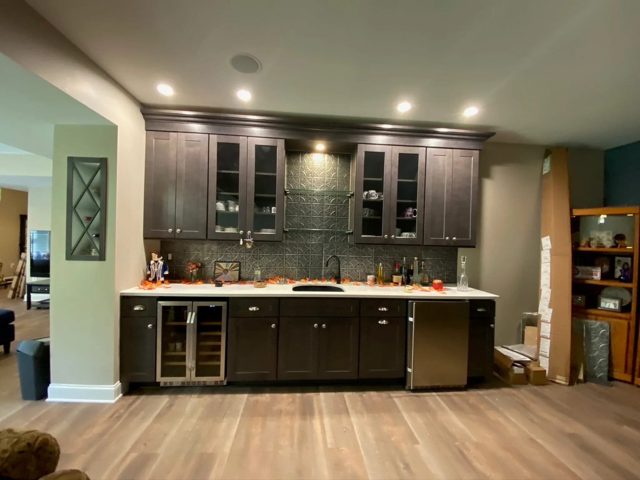 Dark cabinetry kitchen with tin tile backsplash, quartz counters, and stainless steel appliances
