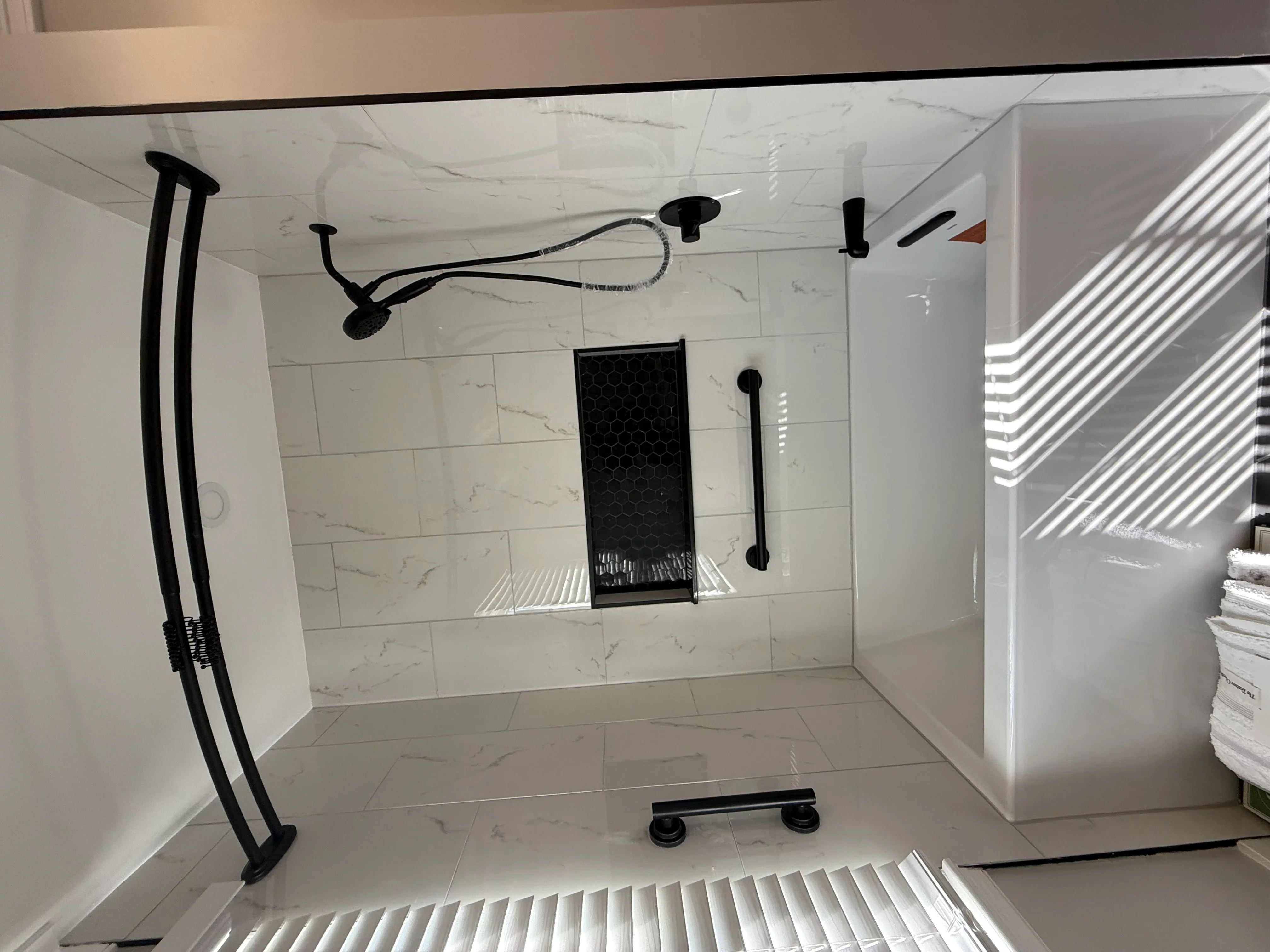 Marble tile shower with frameless glass enclosure and matte black fixtures