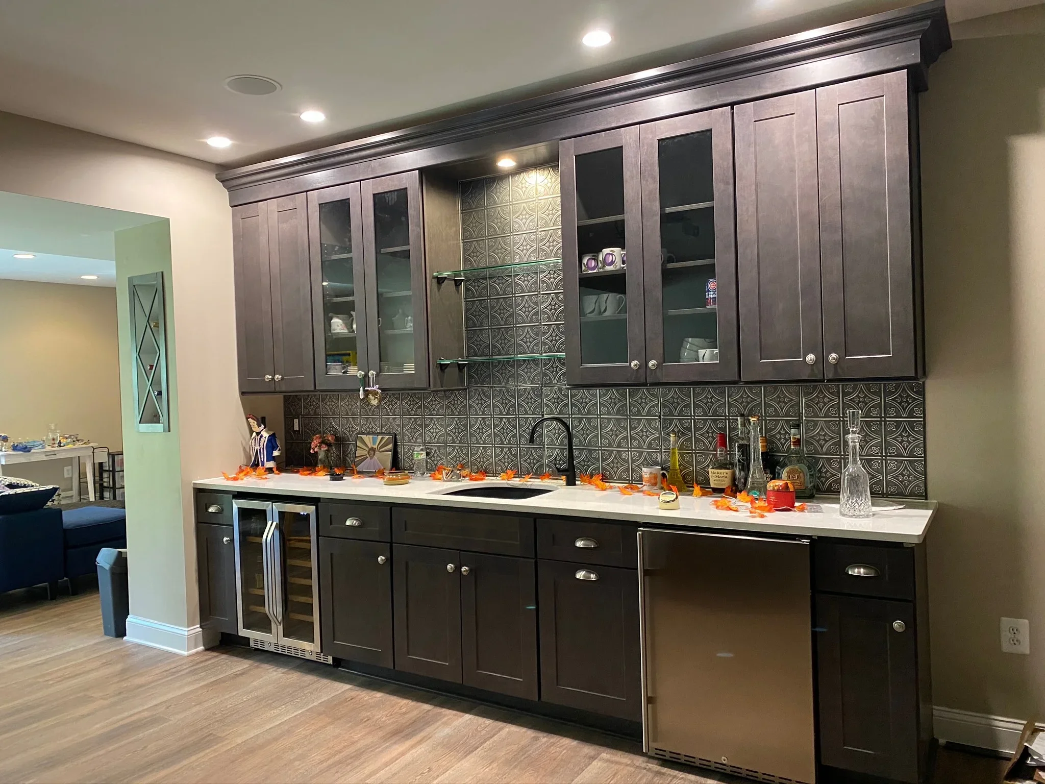 Dark wood kitchen cabinets with glass doors, white quartz countertop, geometric tile backsplash, stainless steel appliances